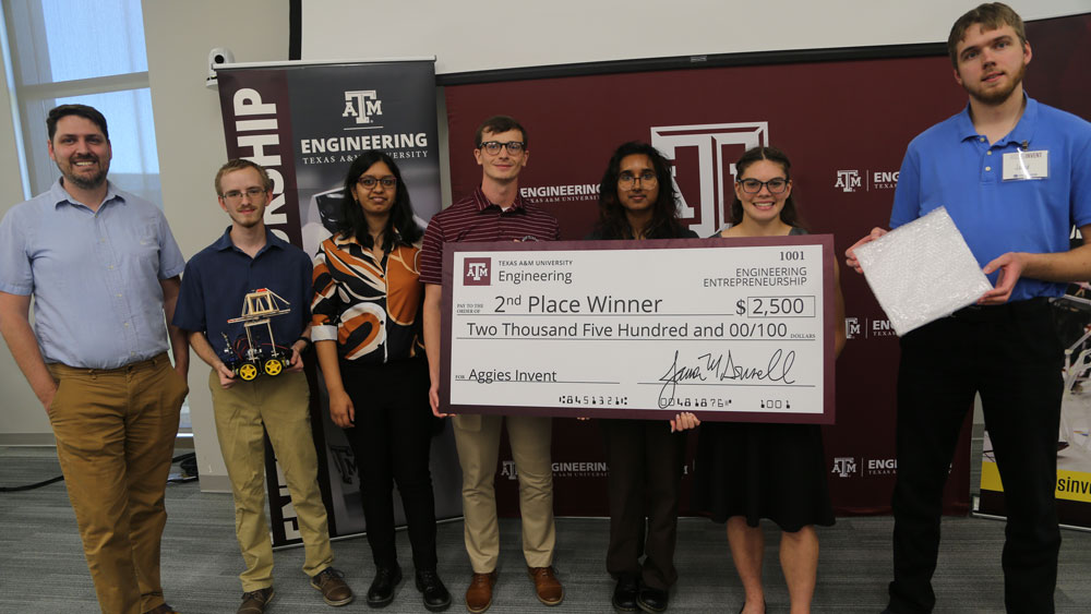 Seven students from Team Paladin holding their second-place oversized check for $1,500.