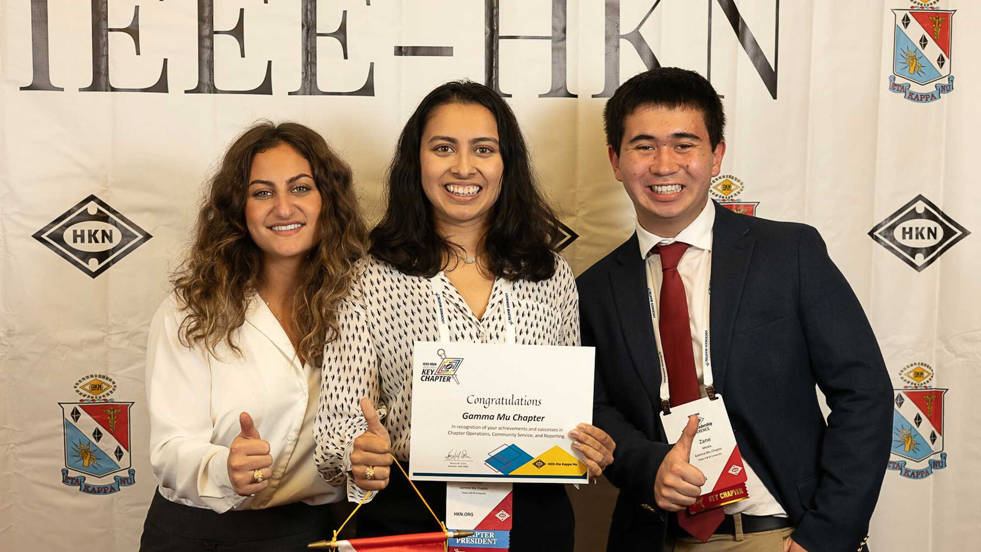 An image showing three HKN members accepting the Key Chapter Award and posing together for a photo with the certificate.