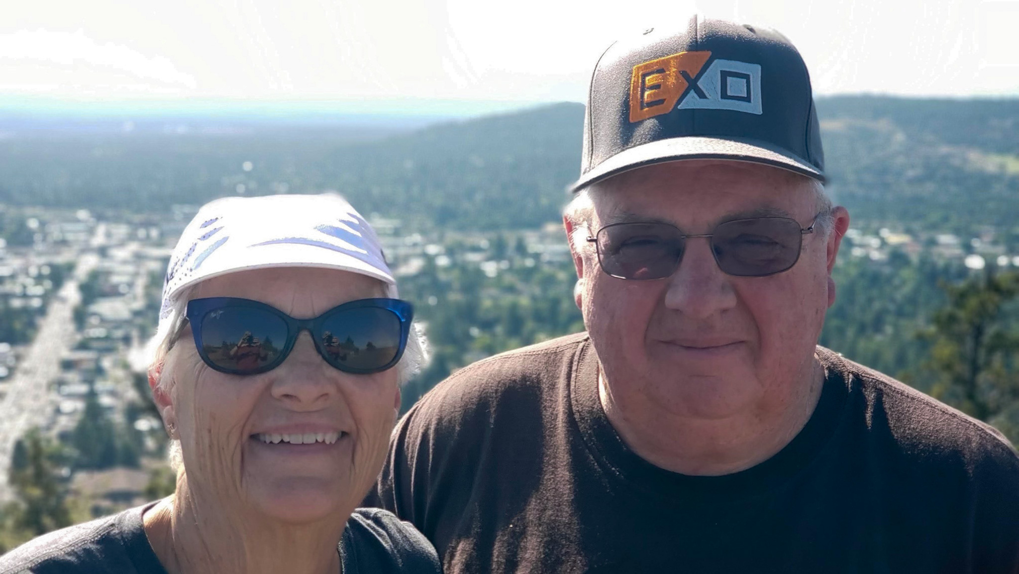  Denise and Wesley Oliphant smiling at the camera with a skyline in the background.