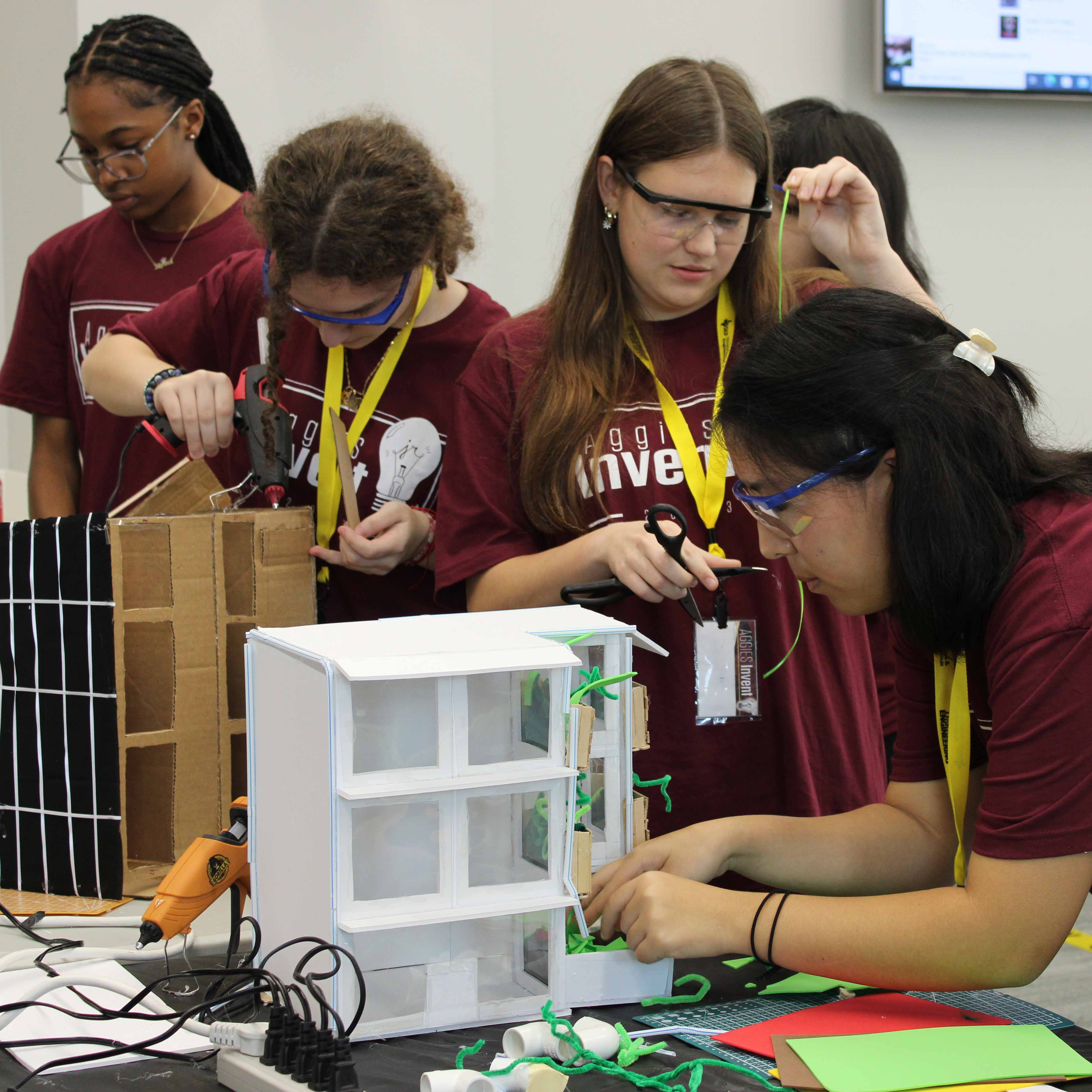 Four high school females working on their projects at a table.