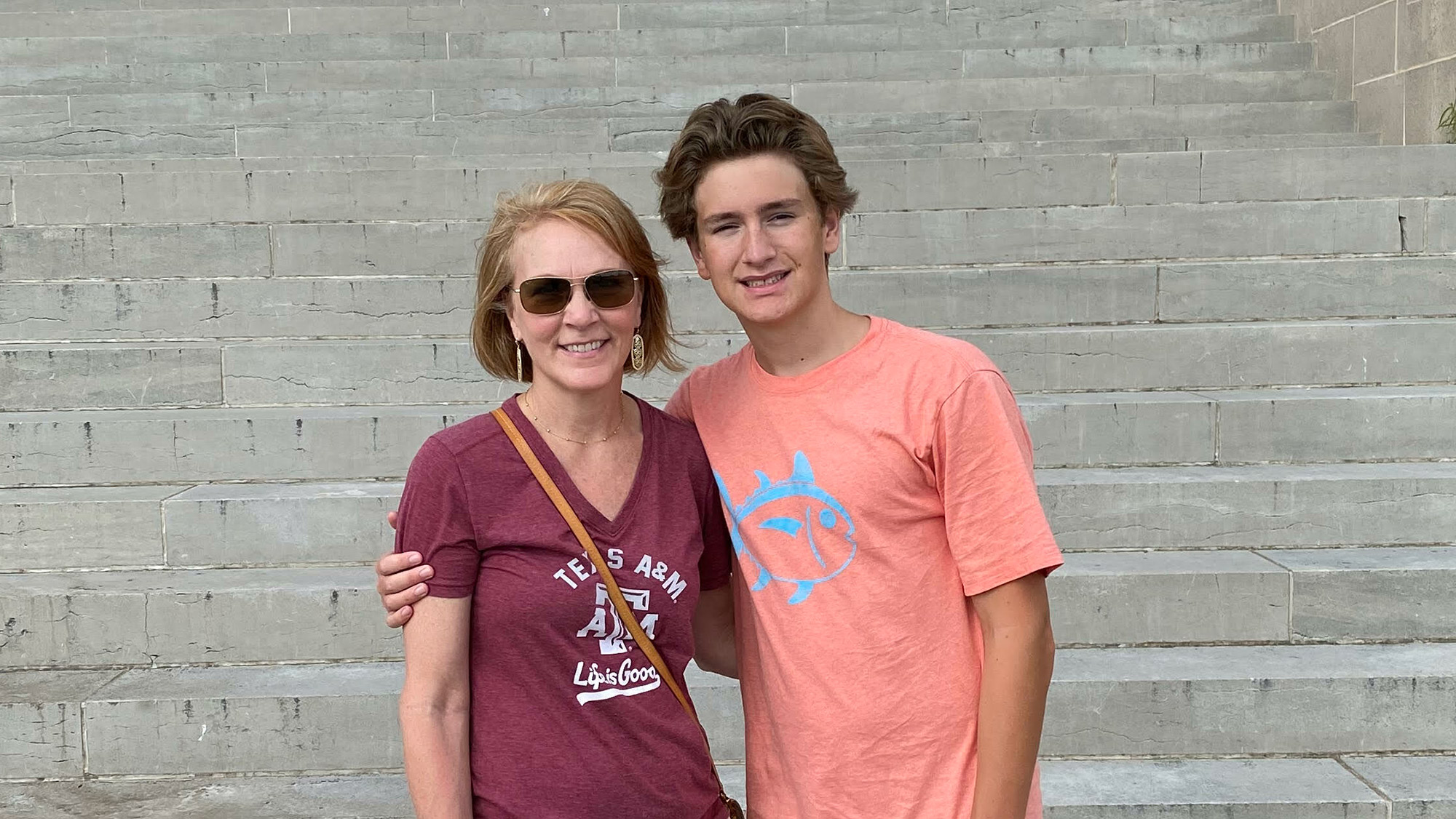 A mother and son posing on the steps of a building.