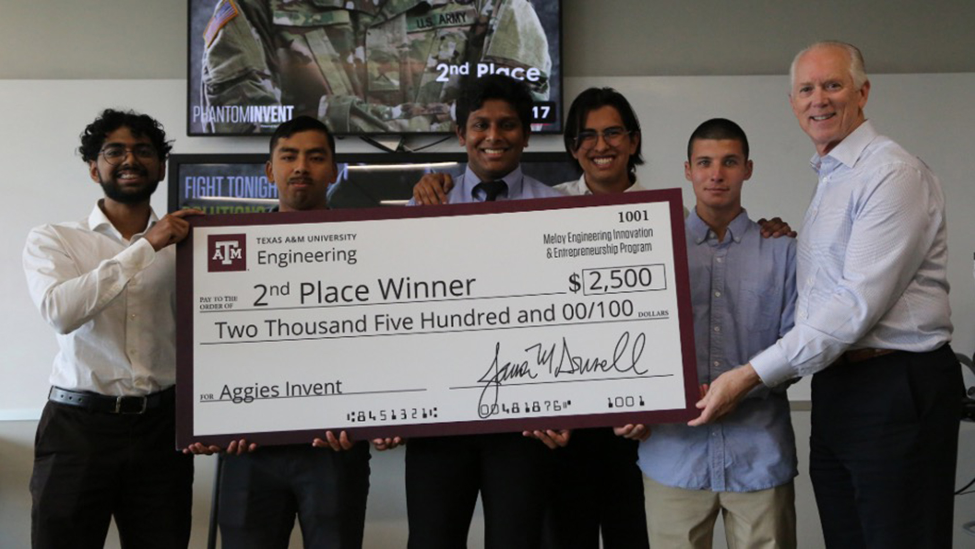 Students holding a large check for $2,500 that says second place winner.