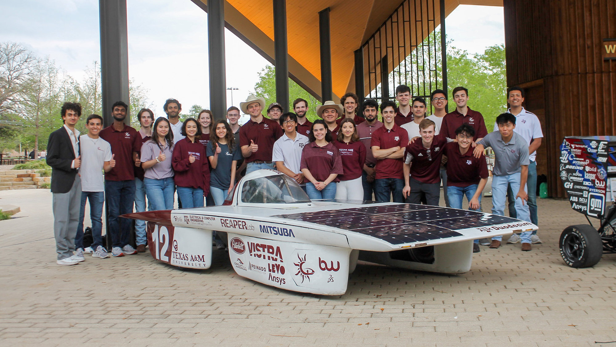 A group of students stands around a solar vehicle.