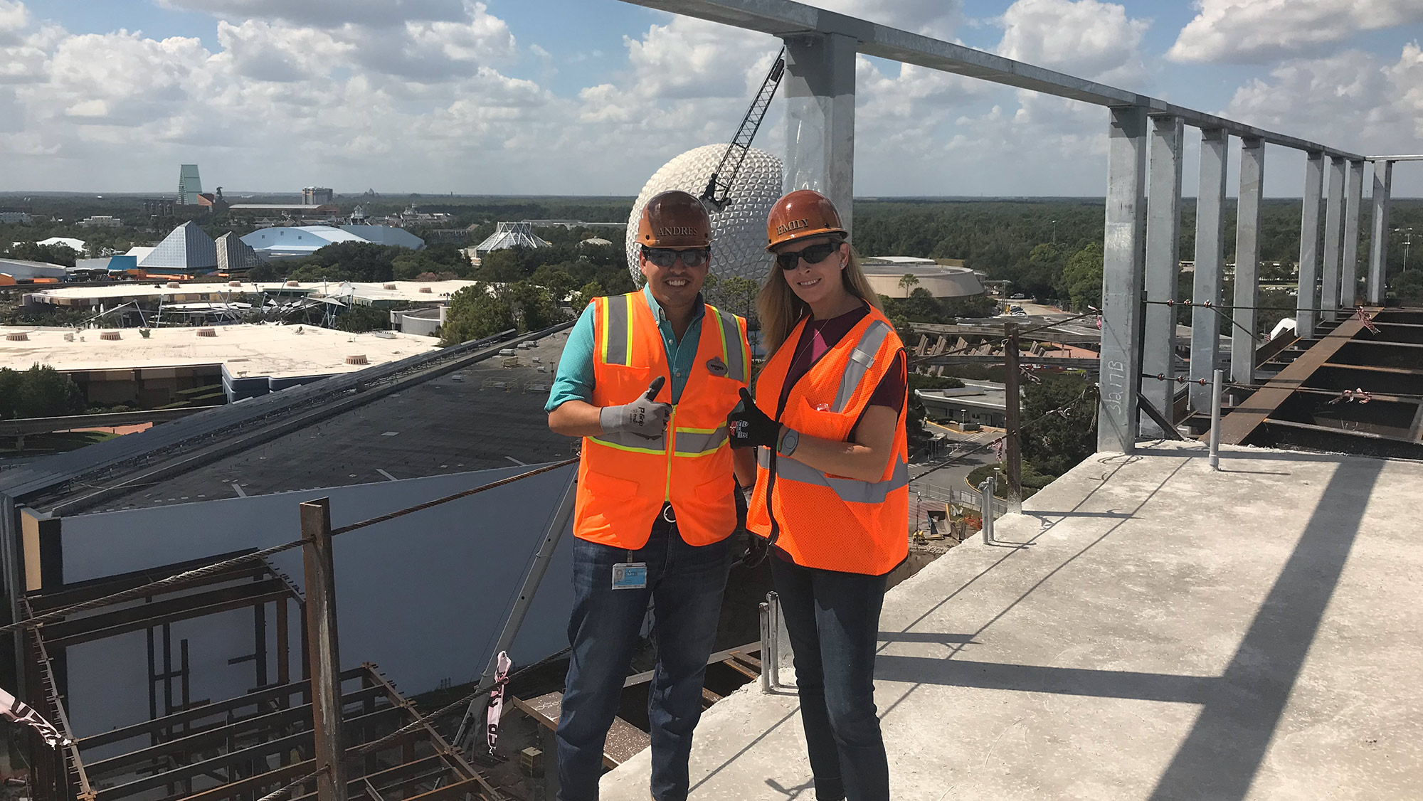 Man and woman pose on top of building.