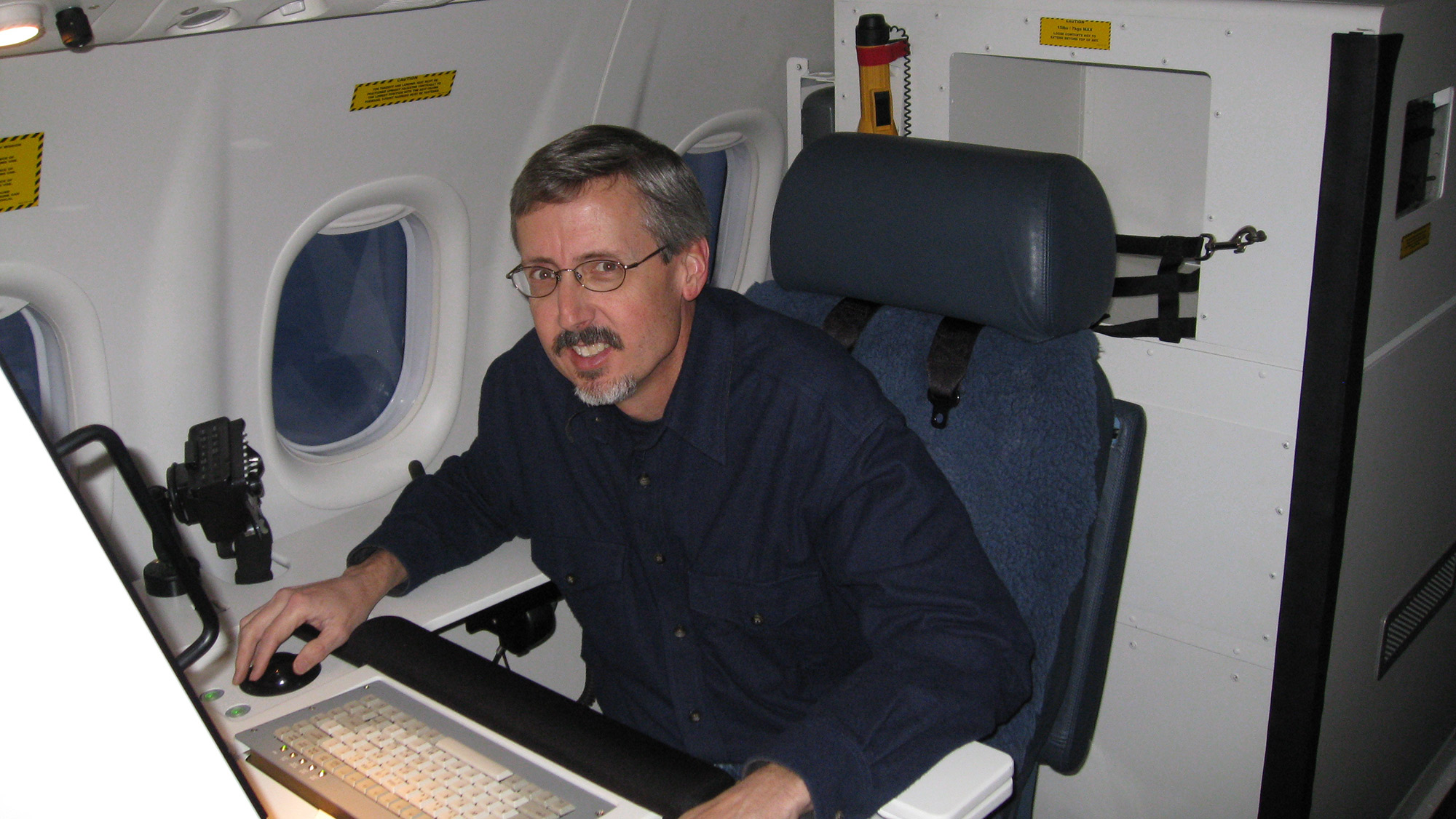 Man sits at a computer on a plane.