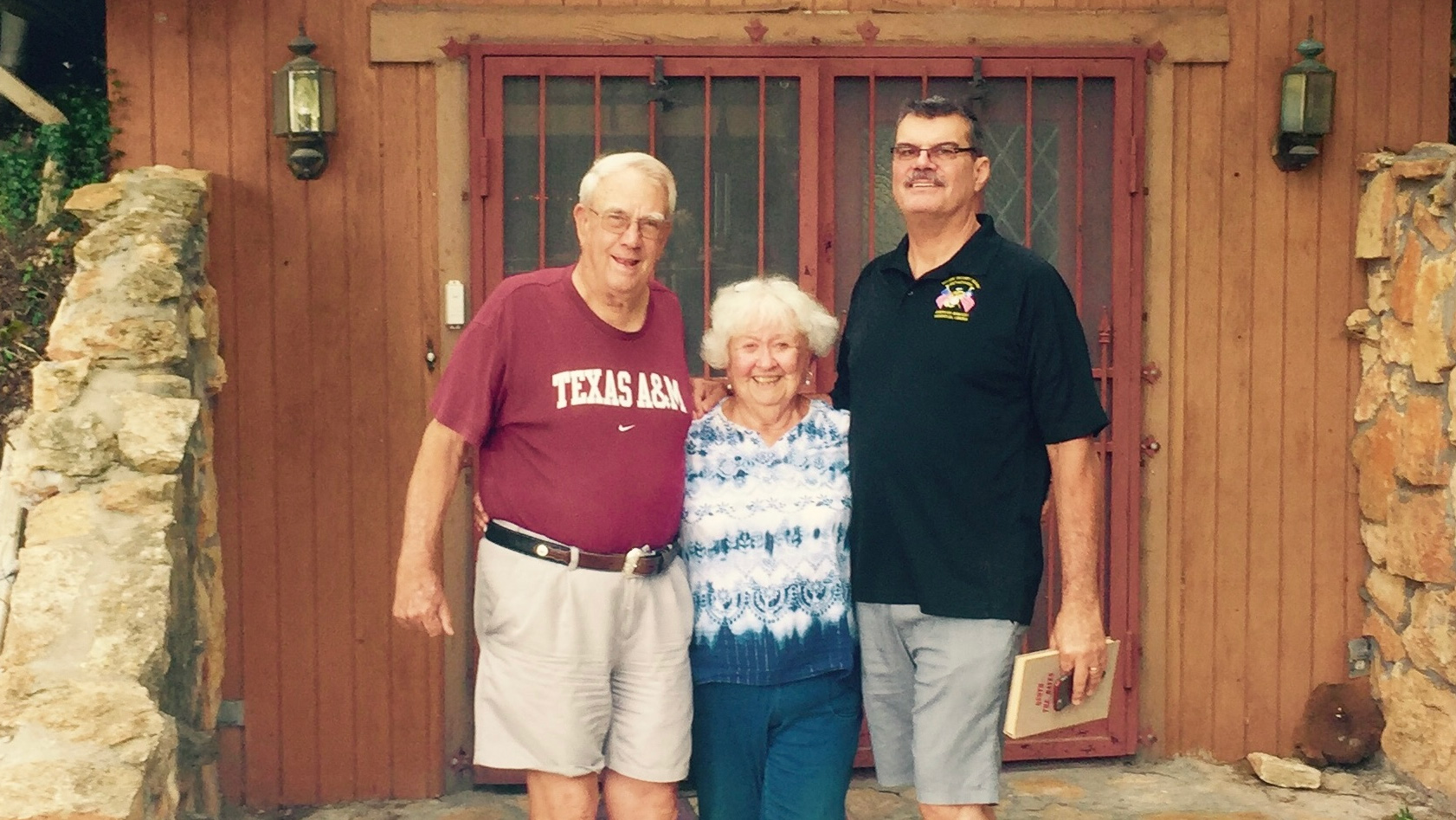 Two men and a woman in front of a house