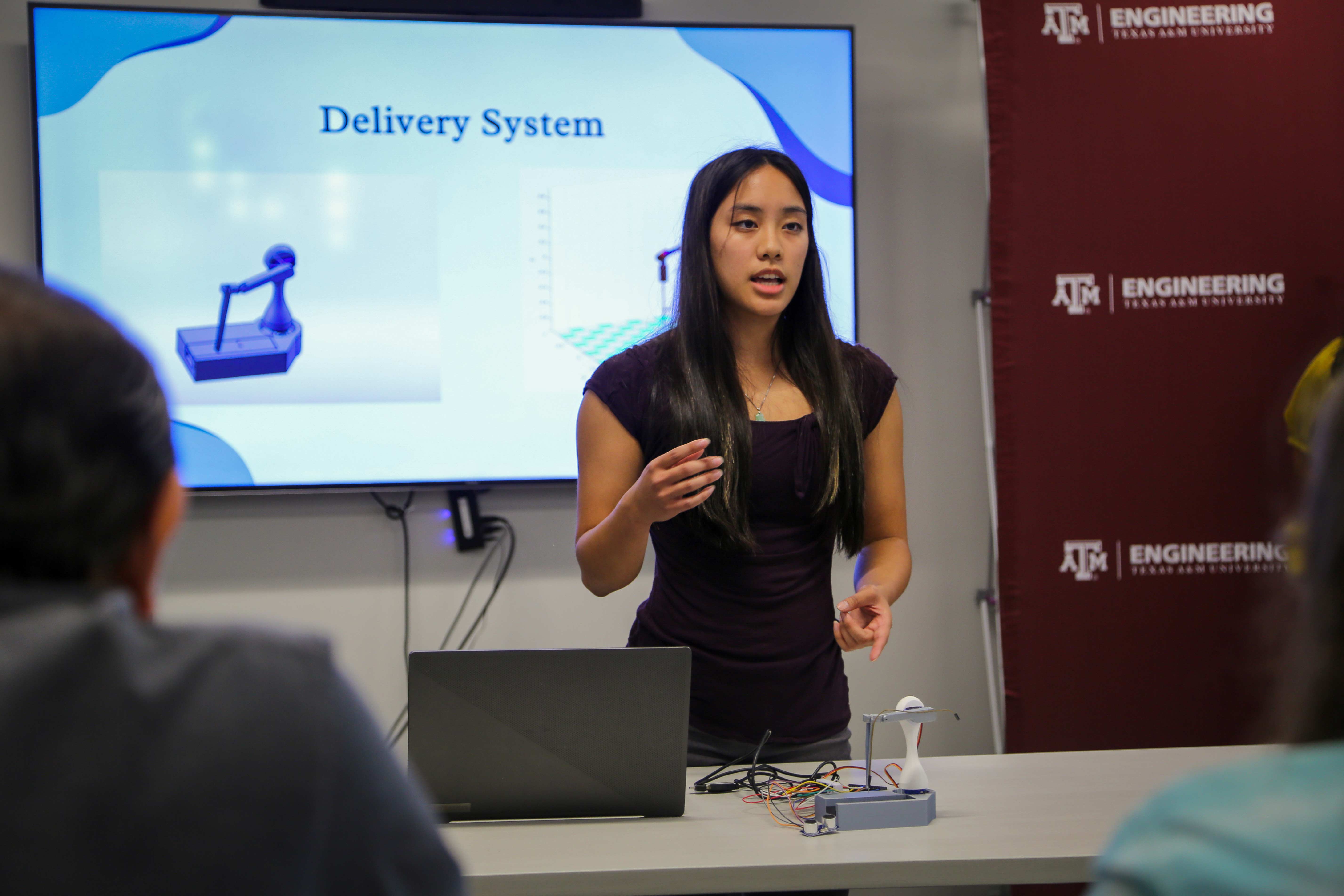 Student standing in front of a screen giving a presentation.