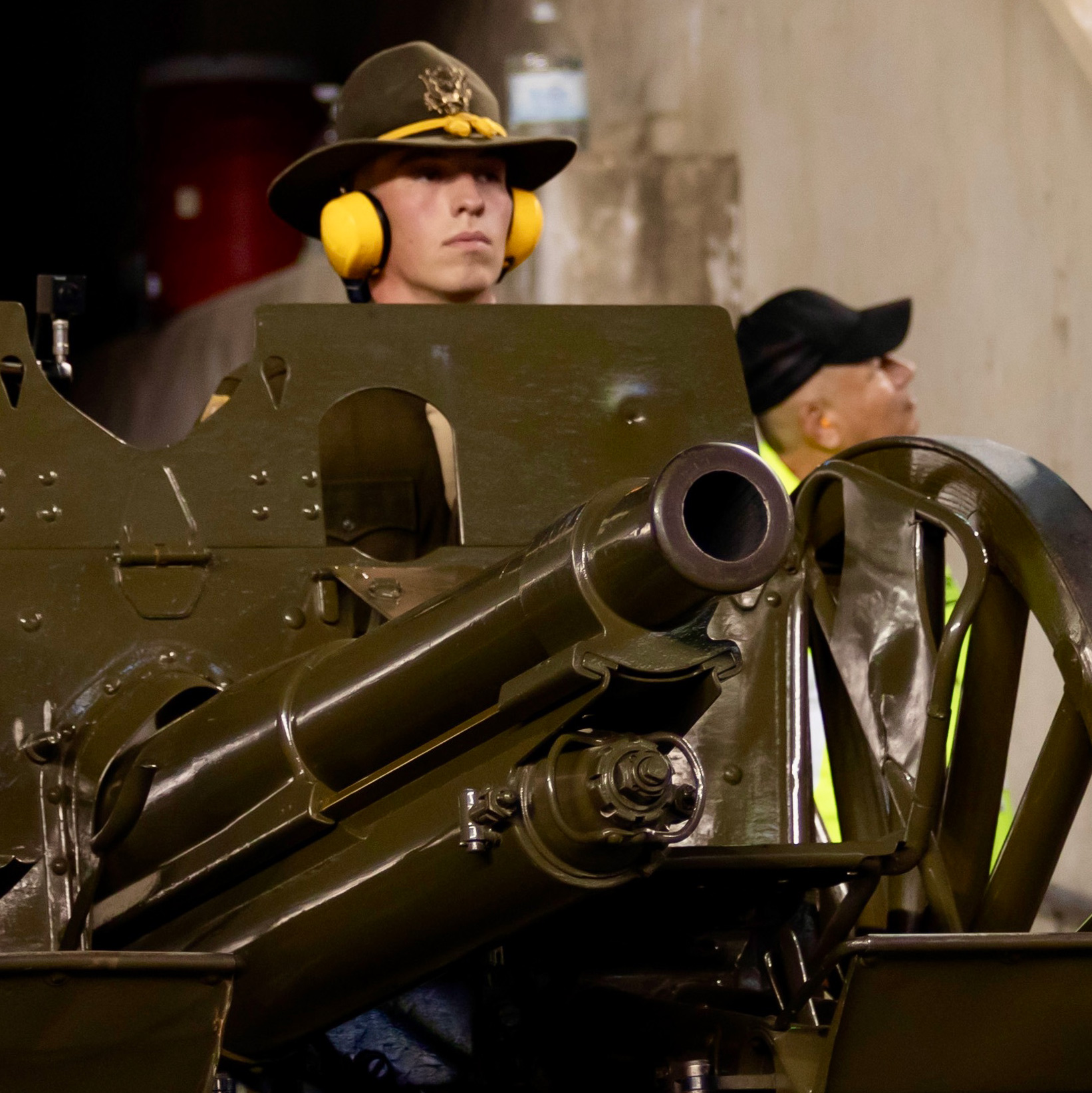 Four people stand behind a cannon with three wearing Texas A&amp;M Corps of Cadet uniforms.