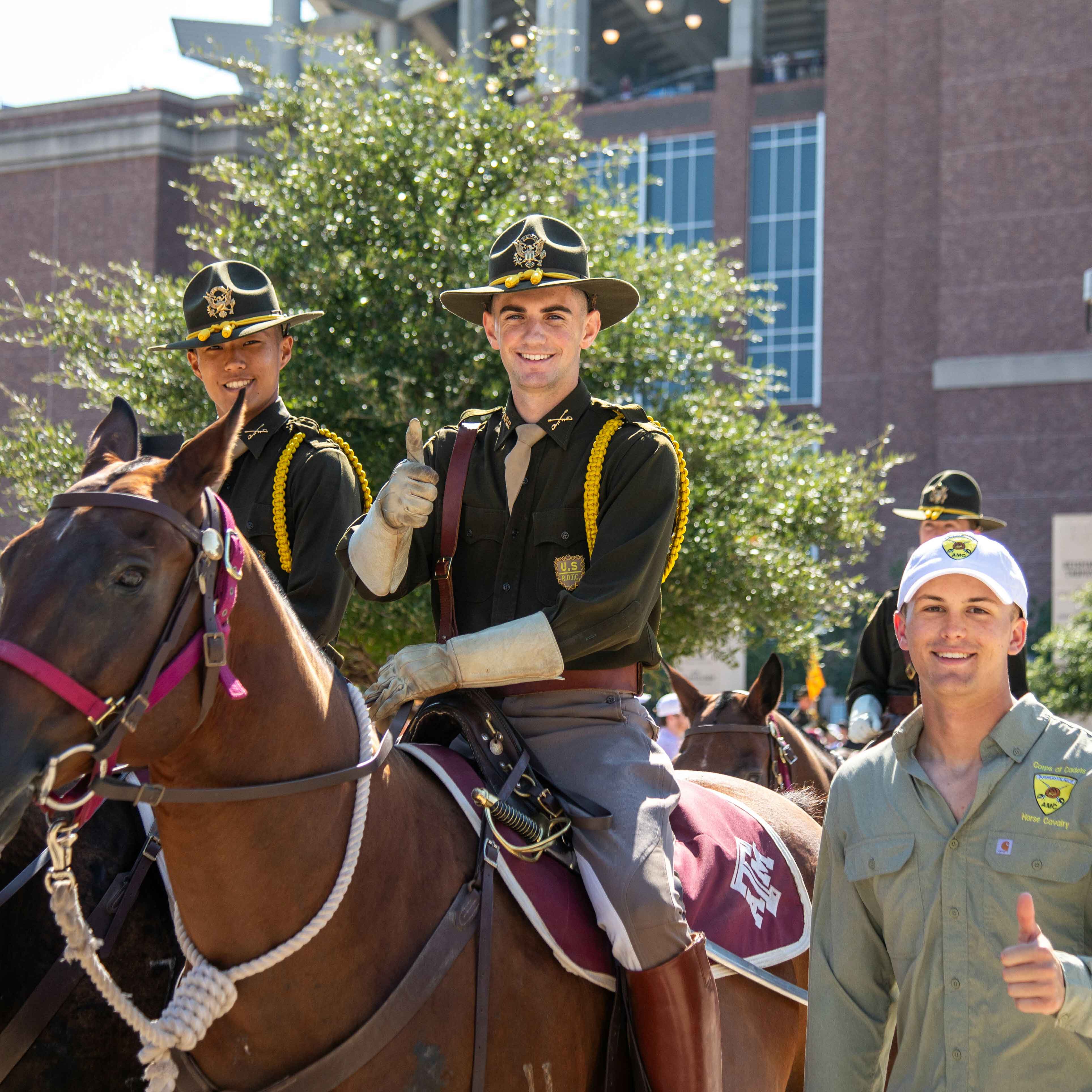 A group of uniformed cadets, five astride brown horses, in front of Kyle Field.