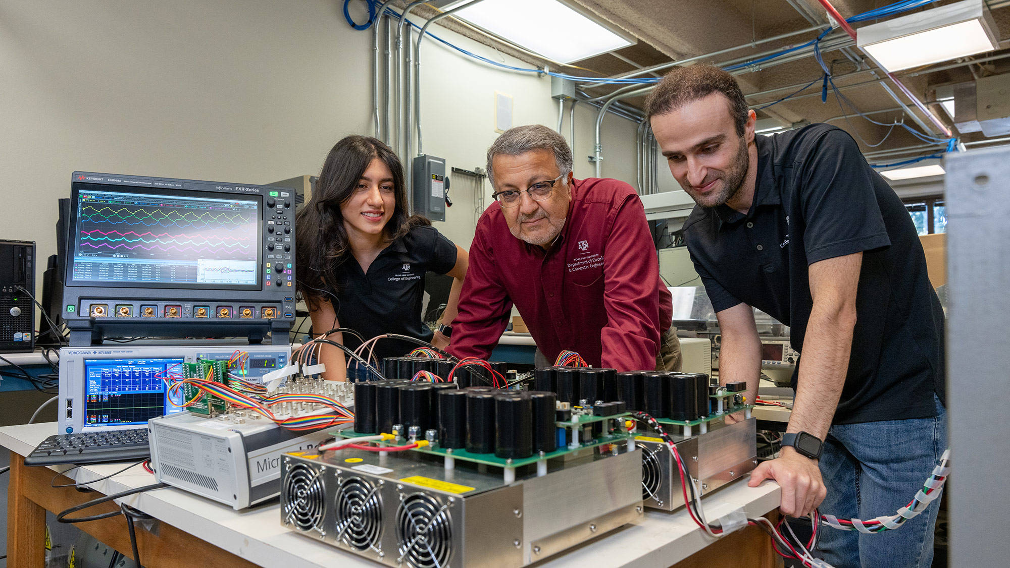 Three people standing in front of a table with motor and sensor technology. 