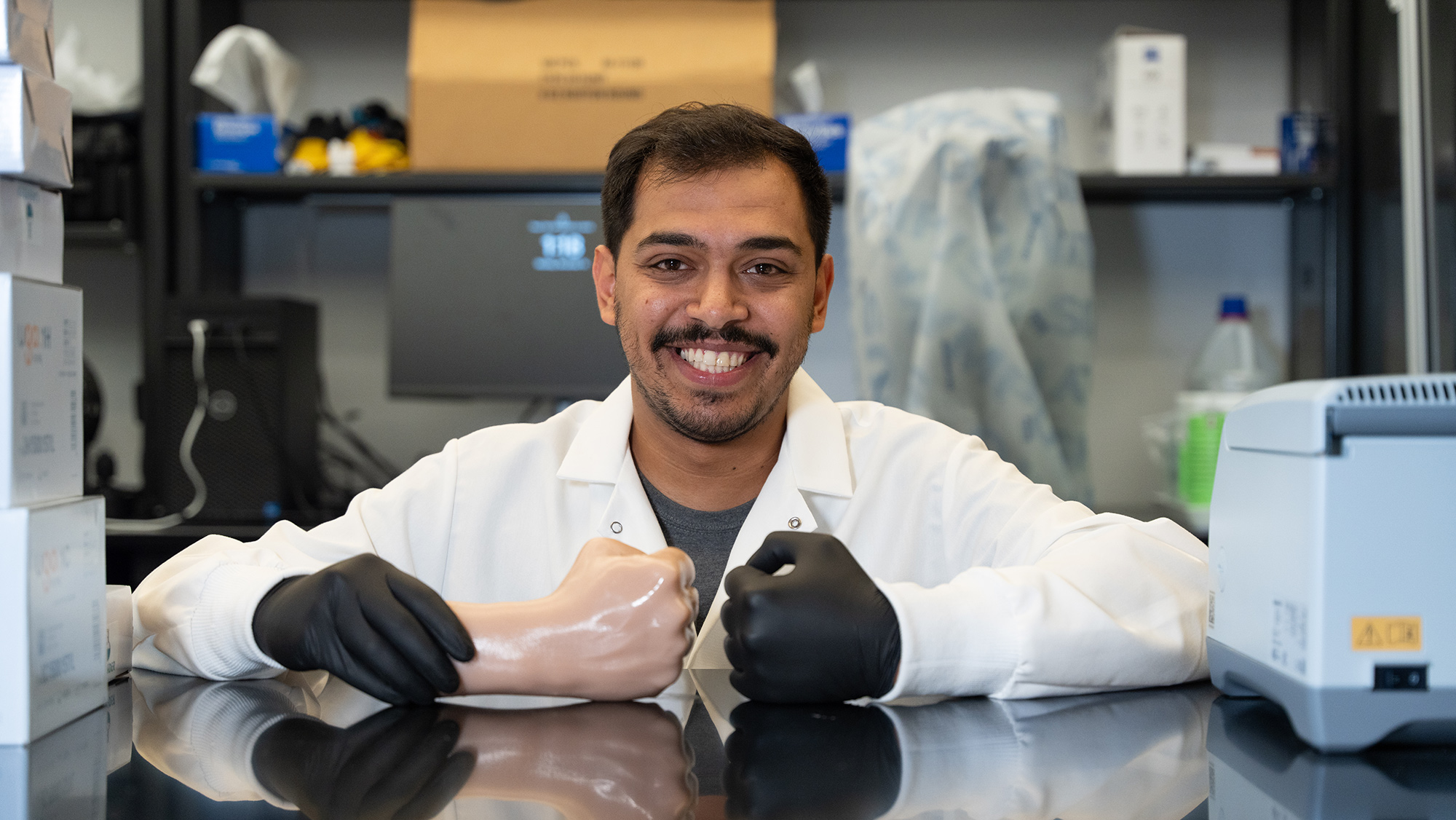 A man smiling holding a hand replica made of Ecoflex.