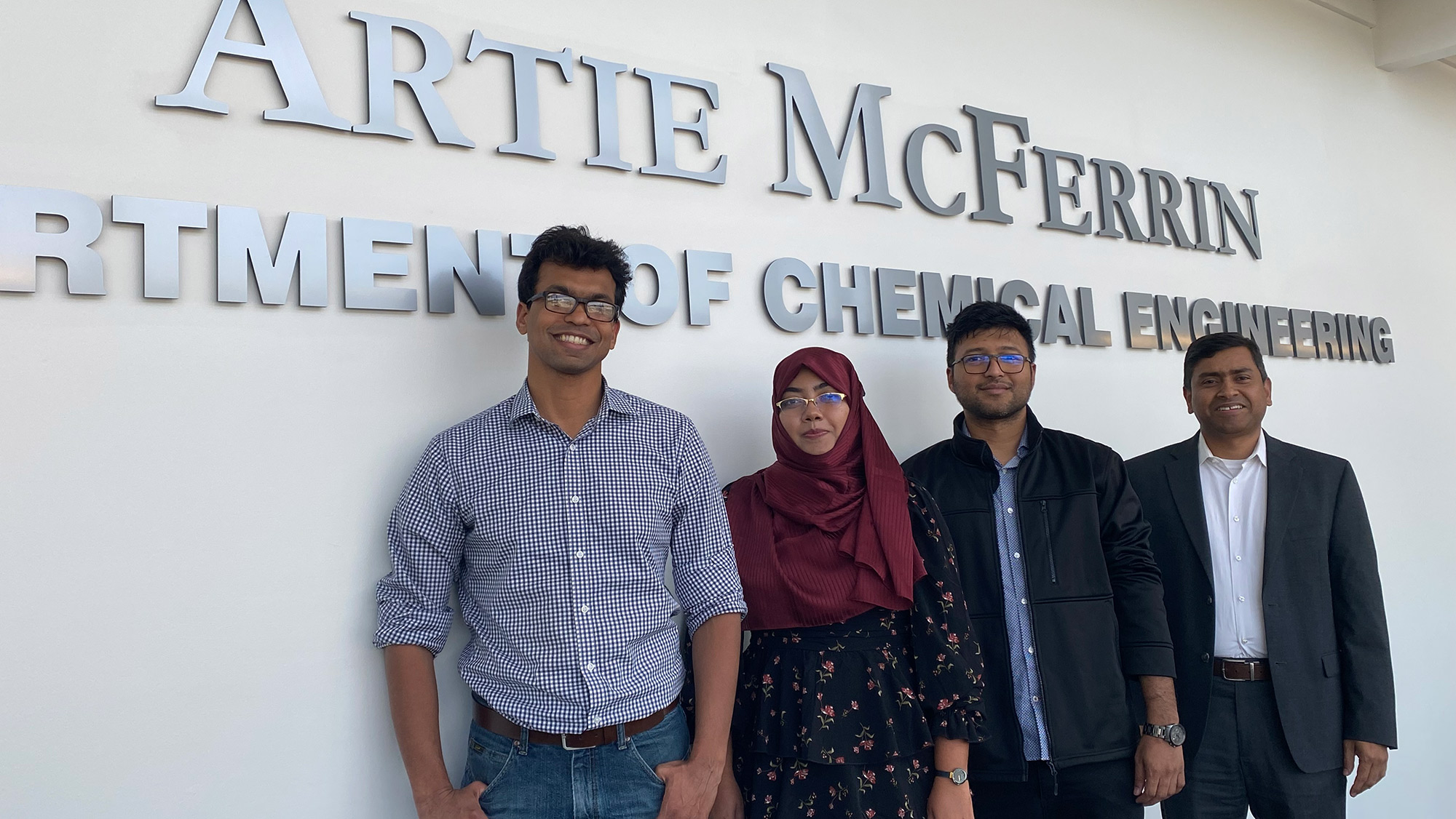 Four individuals pose in front of a sign that reads Artie McFerrin Department of Chemical Engineering.