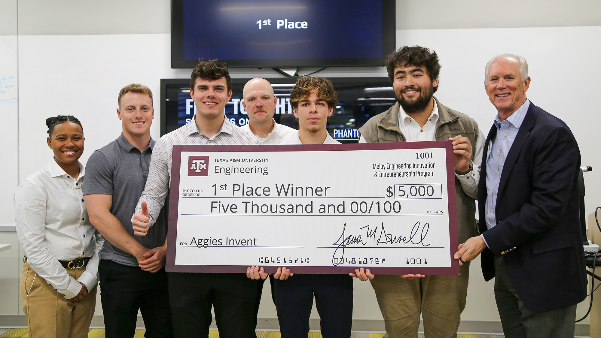 A group of people hold a large check for $5,000.