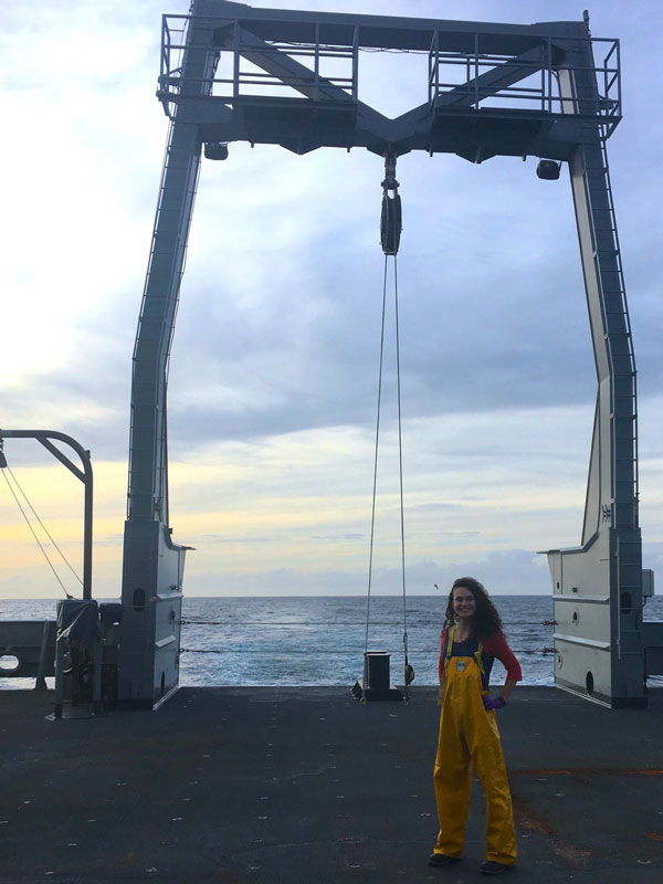 Loicka Baille standing with oceanography equipment on the boat used in the Global Ocean Ship-based Hydrographic Investigation Program (GO-SHIP) Cruise