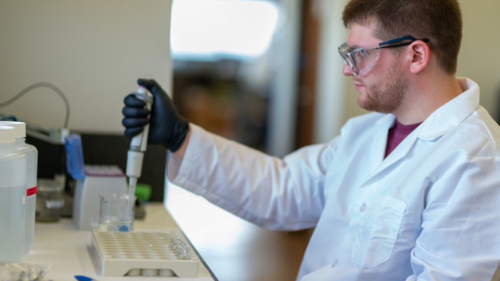 Male petroleum engineering student at Texas A&amp;M University injecting measured amounts of a sample into the compartments of a testing tray